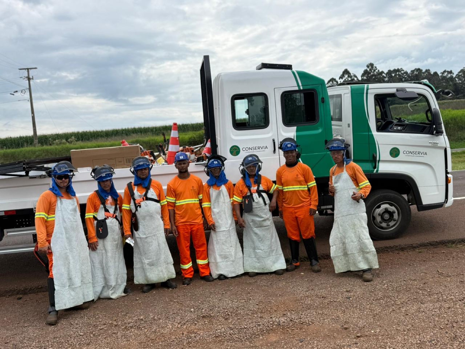 Equipe de roçada da Conservia com EPIs completos diante do caminhão